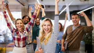 Equipe de collaborateurs coopérants, heureux et avec un sentiment d'appartenance qui lèvent les bras vers le ciel