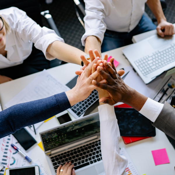 Equipe en entreprise qui joignent leurs mains suite à un bon esprit d'équipe et un management coopératif
